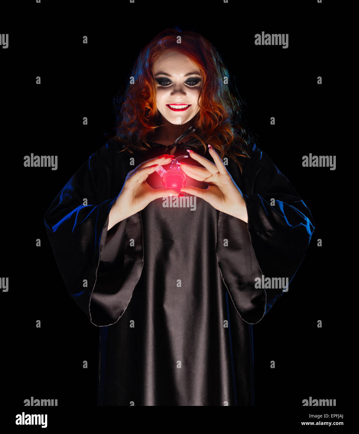 Jeune sorcière avec potion rouge isolé sur black Banque D'Images
