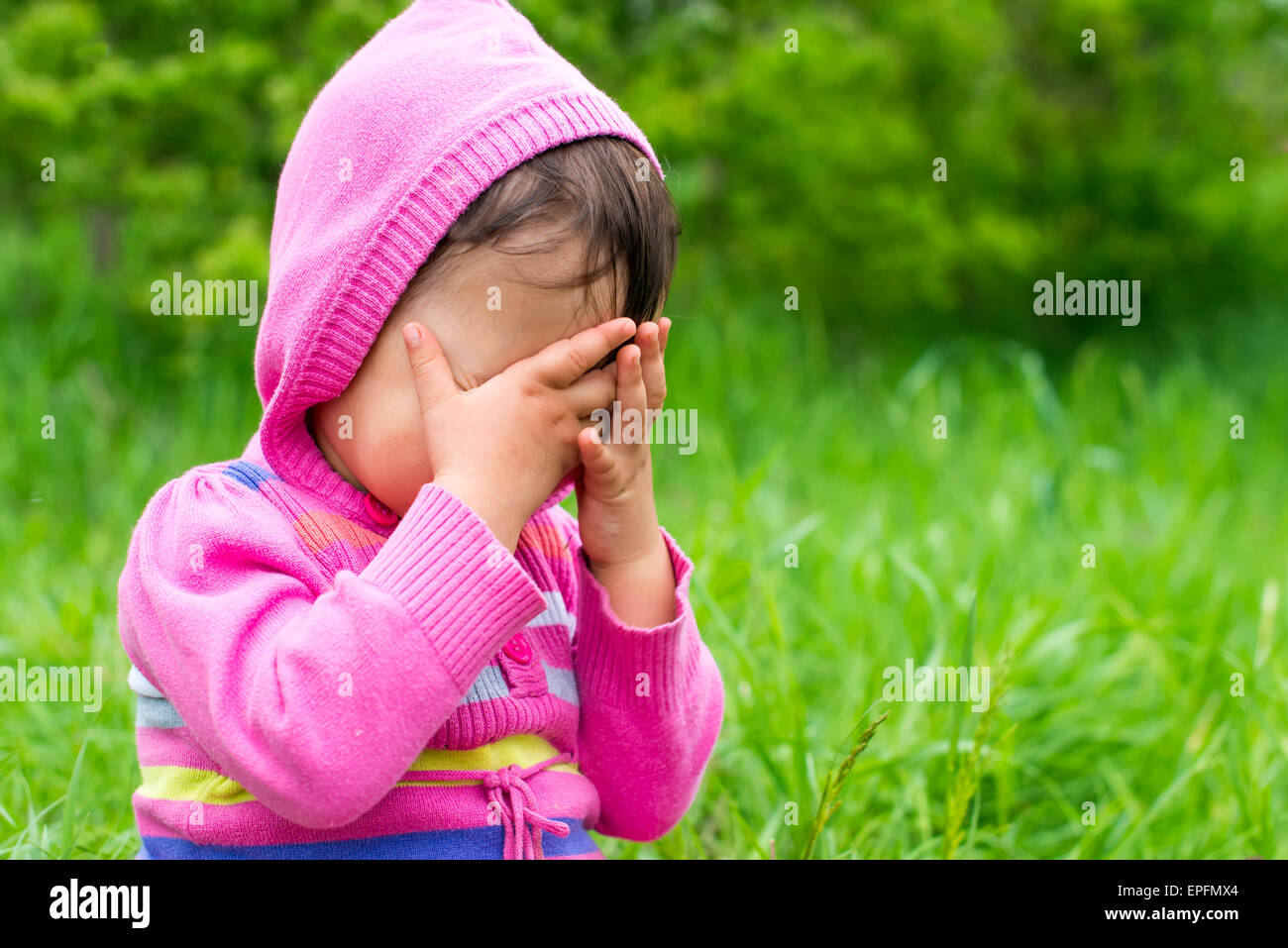 Petite fille joue à cache-cache et de se cacher face Banque D'Images