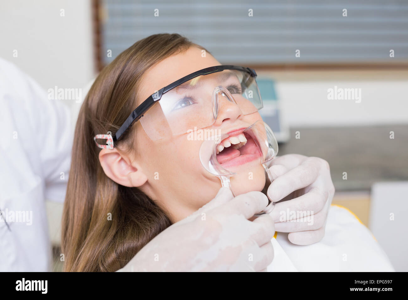 Dentiste mettant l'enrouleur sur la bouche petite fille Banque D'Images