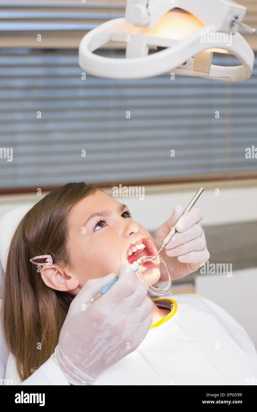 Dentiste à l'aide de l'enrouleur sur la bouche petite fille Banque D'Images