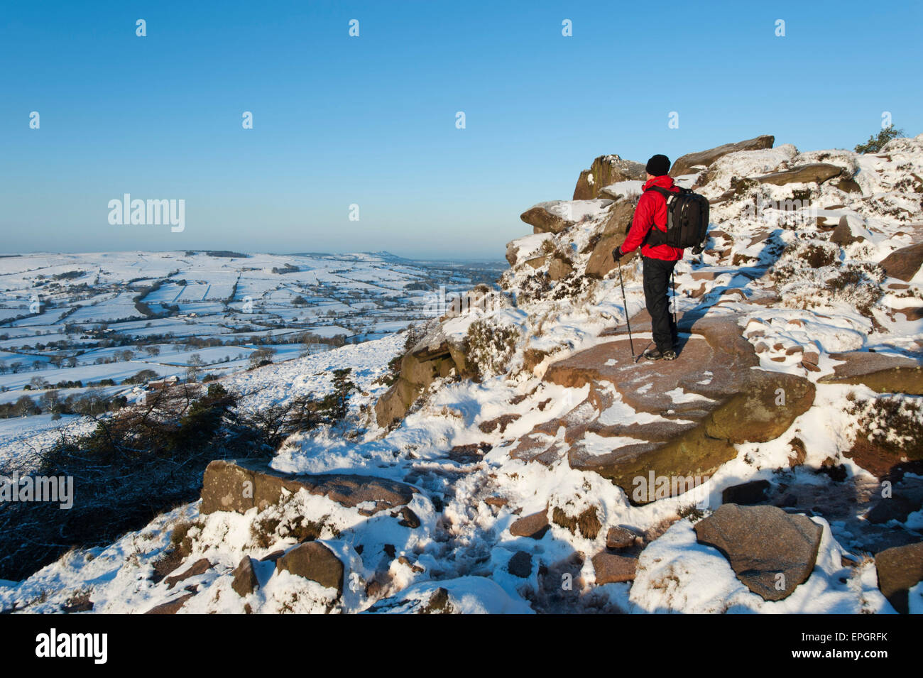 Walker dans la neige admiring view de Bosley Cloud & Cheshire de cafards, le parc national de Peak, Staffordshire, Angleterre. Banque D'Images