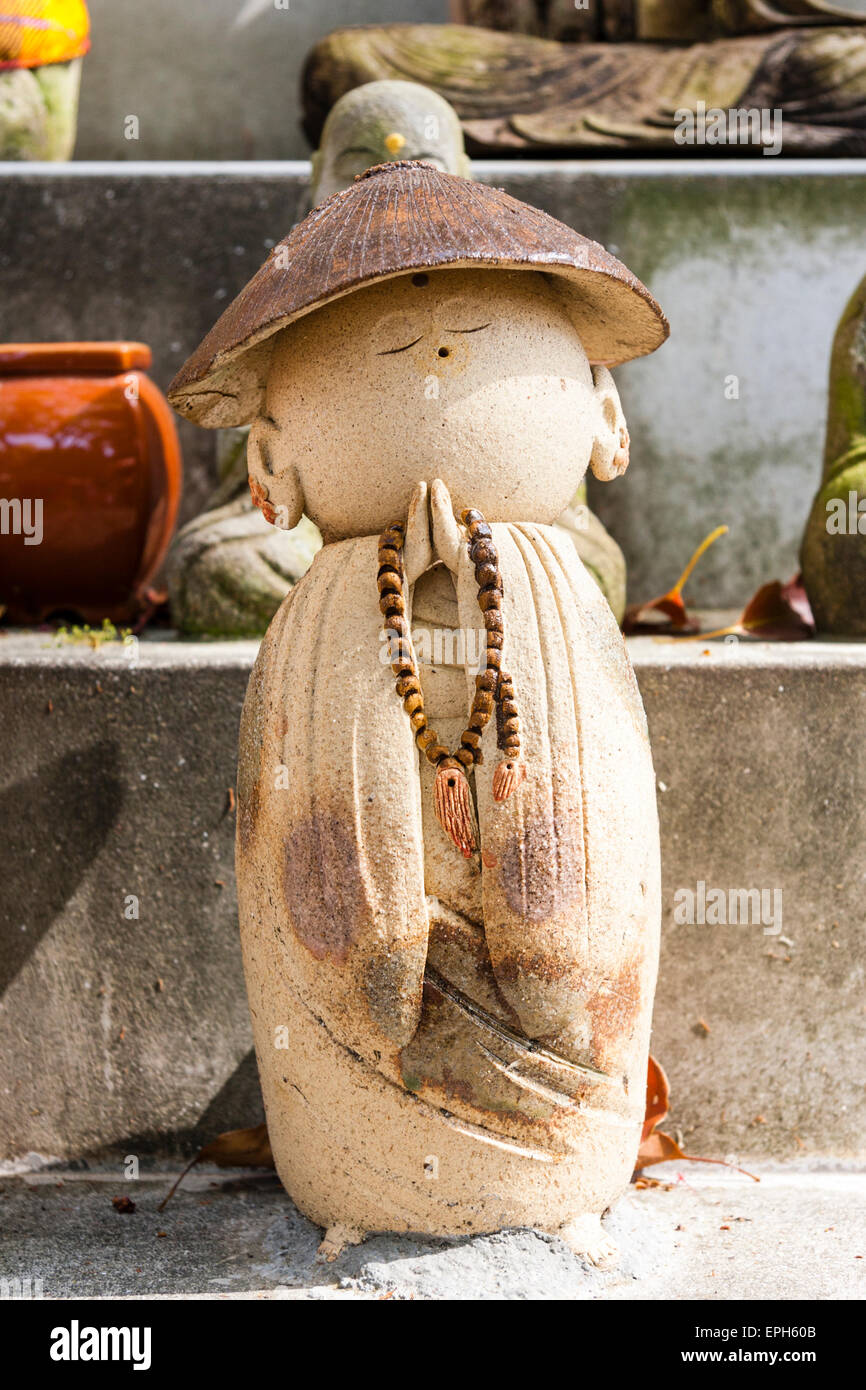 Petite statue de Jizo Bosatsu au temple de Suma Dera, Japon. Figure est avec chapeau conique d'un prêtre bouddhiste, les mains claspées en priant avec rosaire. Banque D'Images