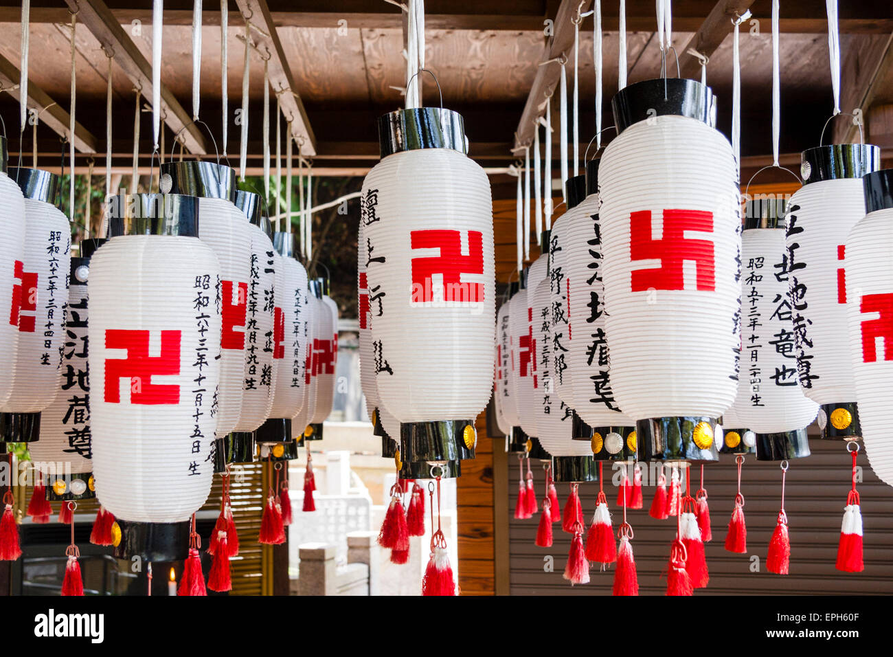 Tableau de lanternes en papier, chois, tous suspendus avec des inscriptions kanji noires et des symboles de paix swastika rouges sur le temple de Suma Dera, Japon. Banque D'Images