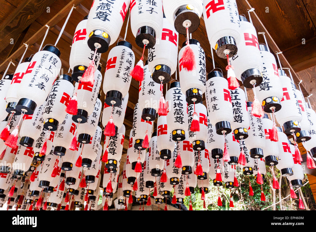 Tableau de lanternes en papier, chois, tous suspendus avec des inscriptions kanji noires et des symboles de paix swastika rouges sur le temple de Suma Dera, Japon. En hauteur. Banque D'Images