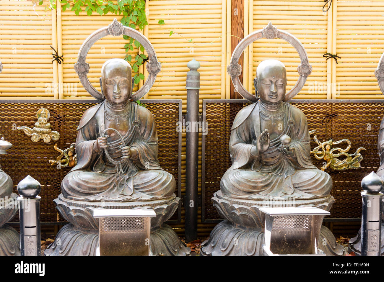 Deux statues de Jizo Bosatsu, situées sur des socles en pierre contre un mur de bambou moderne au temple de Suma dera à Suma, au Japon. Les deux ont des halo autour de la tête. Banque D'Images
