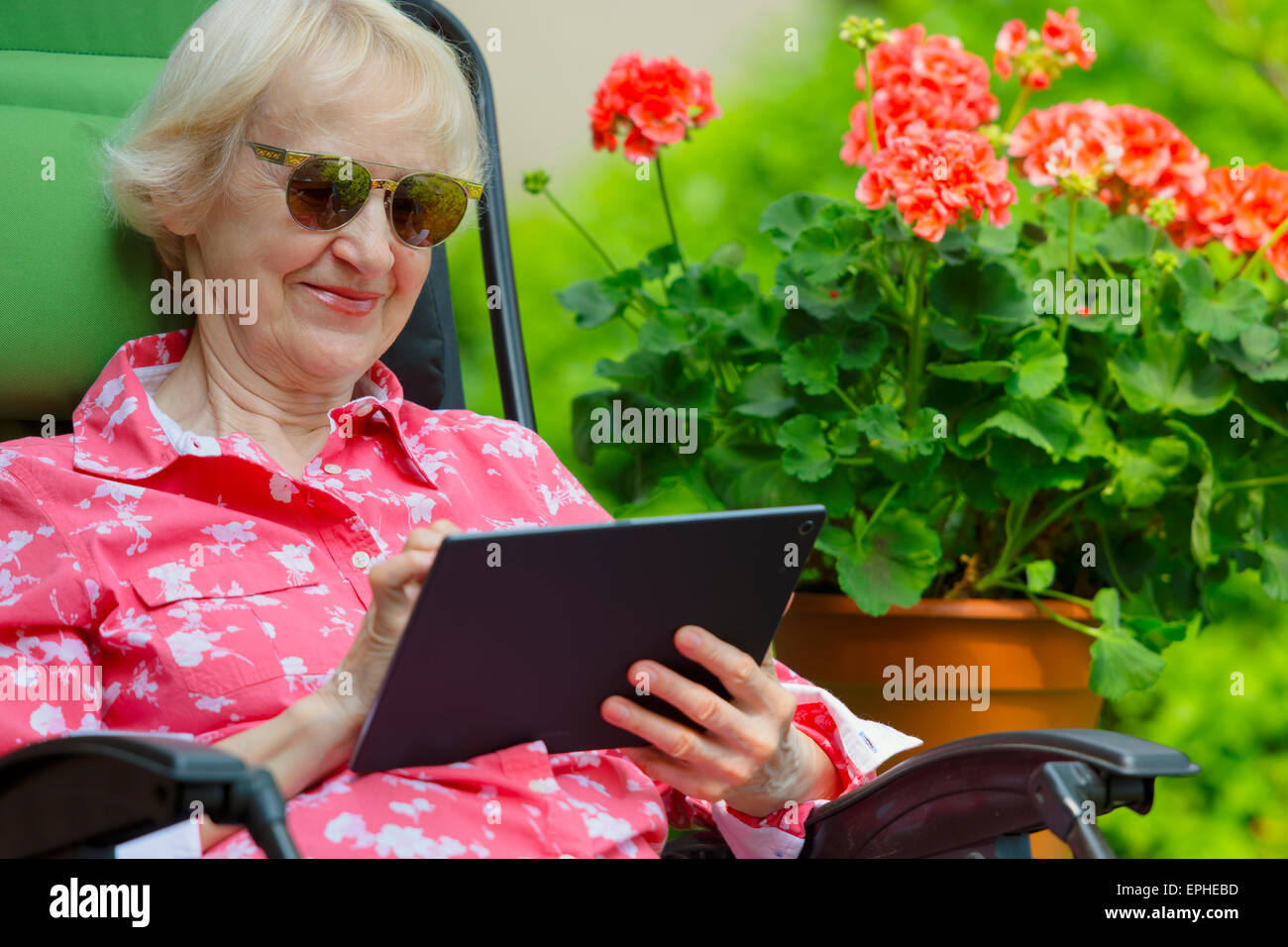 Femme avec tablette, Young Senior à l'extérieur dans son jardin extérieur Lecture Happy Smiling Banque D'Images