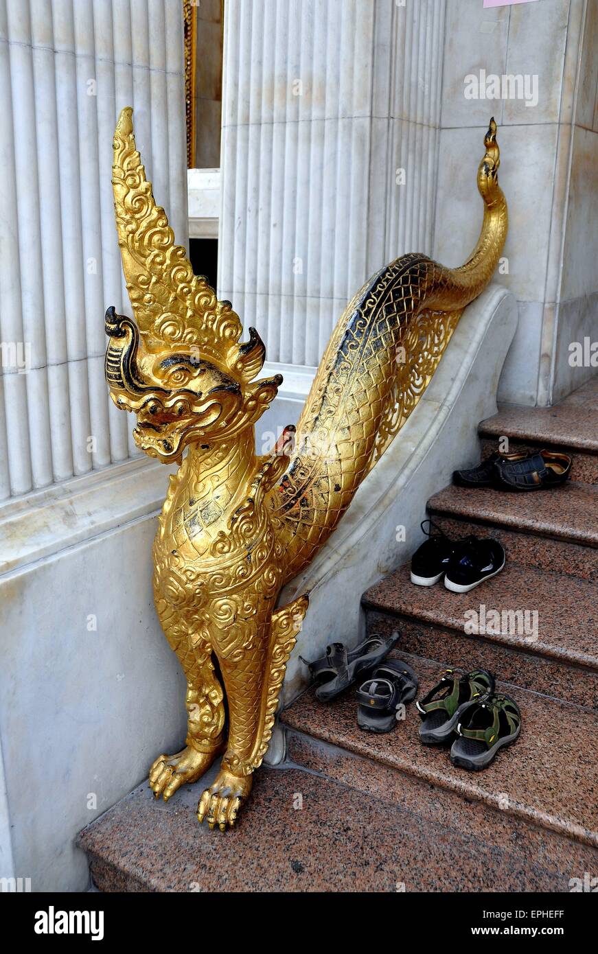 Bangkok, Thaïlande : les espadrilles et les sandales s'asseoir sur les marches à côté d'un dragon doré à naga Royal Wat Boworniwet Banque D'Images