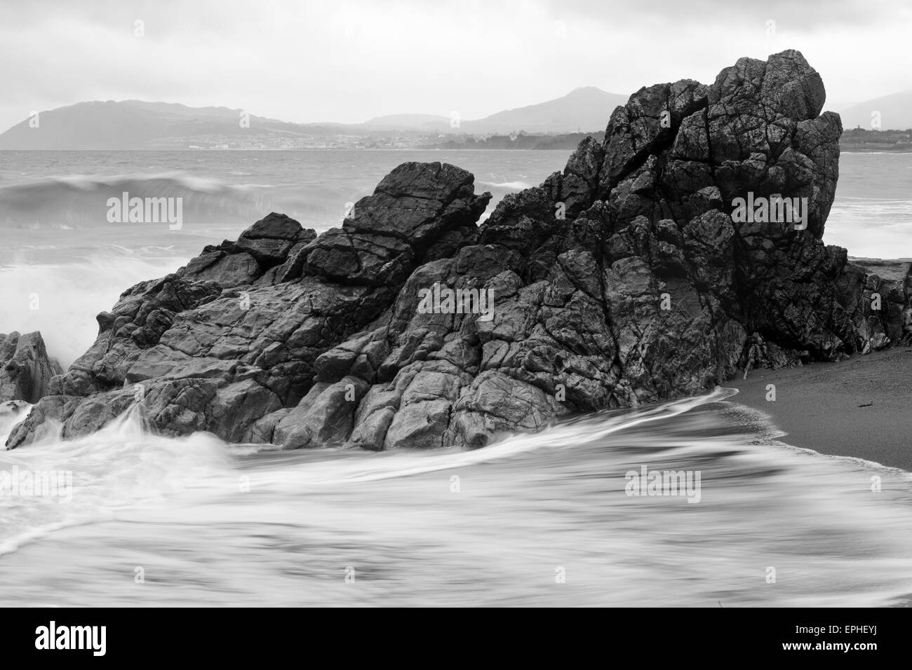 Lap vagues autour de gros rocher sur Killiney beach, Dublin, Irlande. Banque D'Images