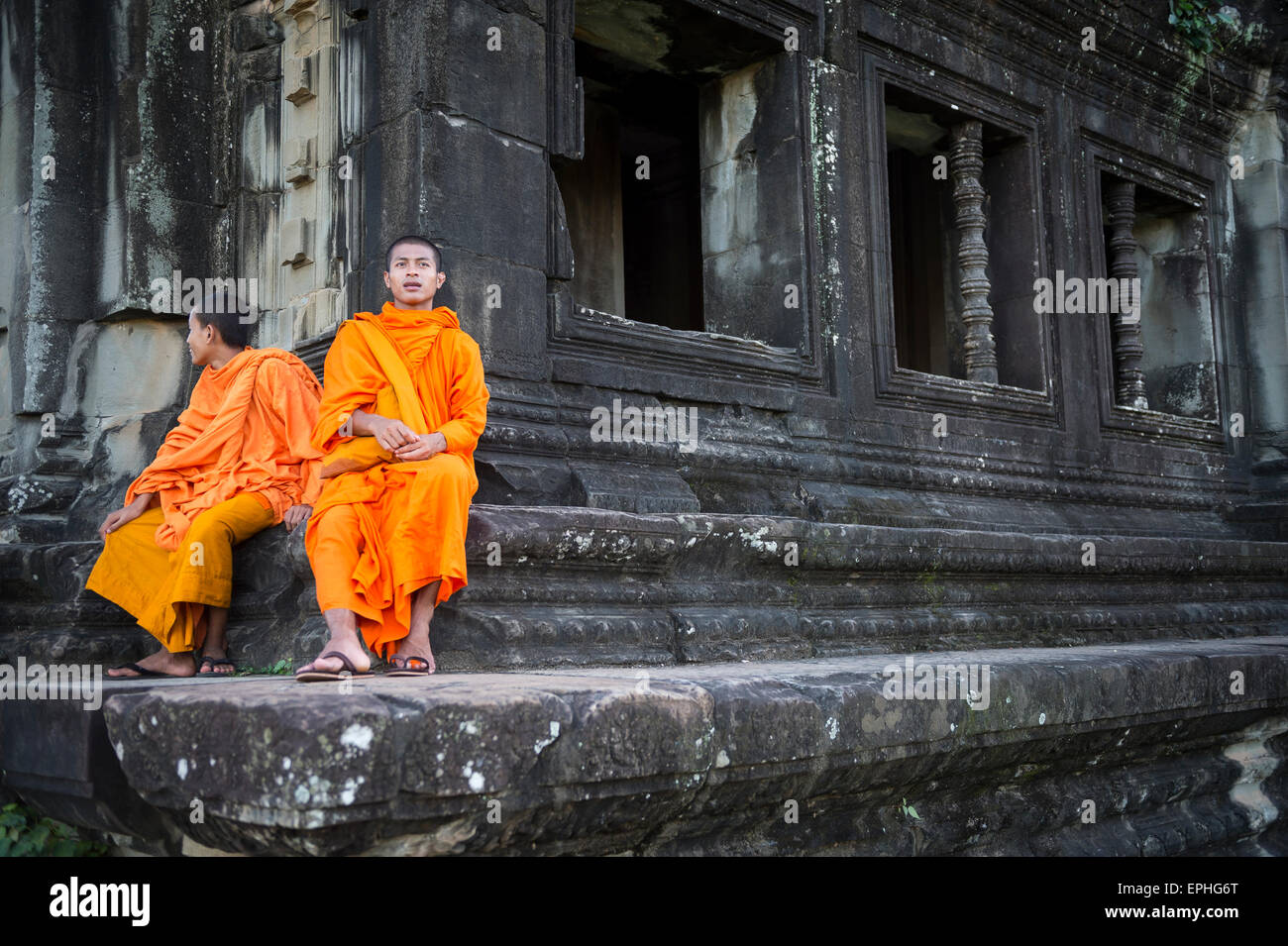 SIEM REAP, Cambodge - 30 octobre 2014 : Paire de novice moines bouddhistes en robe safran s'asseoir à l'extérieur d'un temple d'Angkor Wat. Banque D'Images