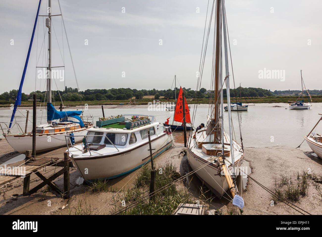 Un miroir canot voiles amarrés yachts au Wivenhoe passé sur la rivière Colne, Essex, Angleterre, RU Banque D'Images