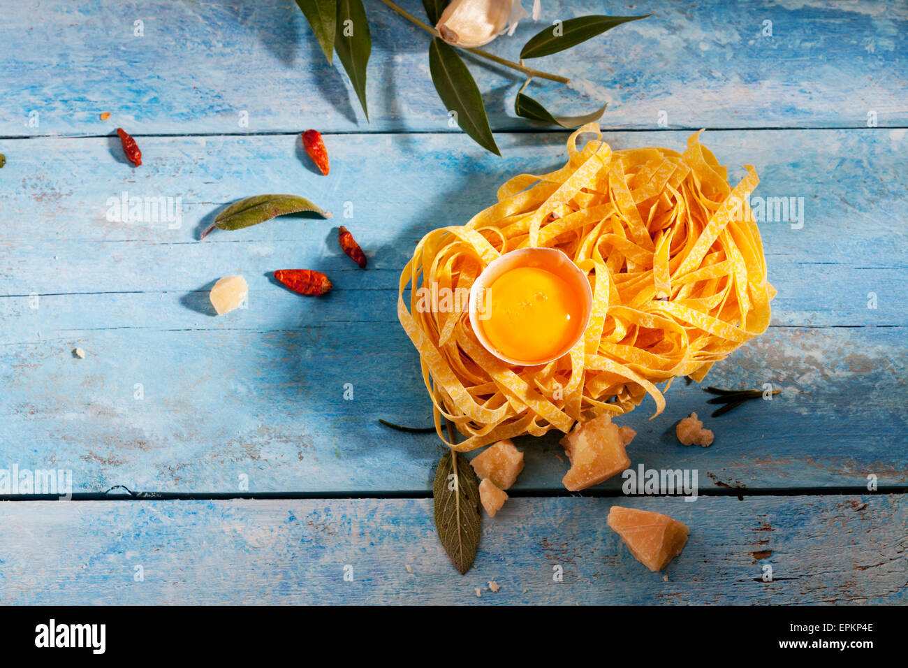 Tagliatelles de matières premières, d'oeuf en coquille, chili les gousses, feuilles de sauge, le parmesan et la gousse d'ail. Banque D'Images