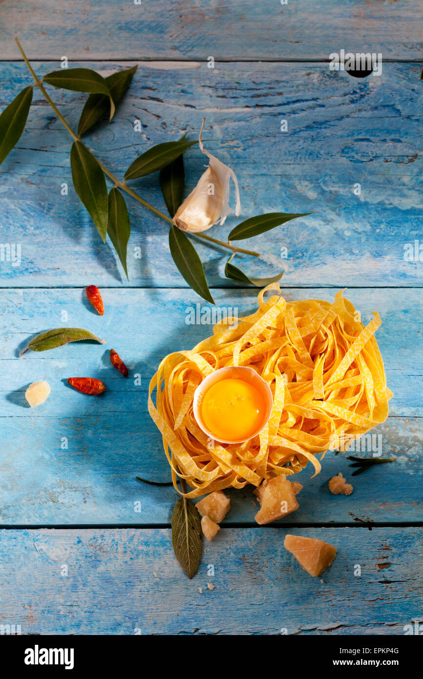 Tagliatelles de matières premières, d'oeuf en coquille, chili les gousses, feuilles de sauge, le parmesan et la gousse d'ail. Banque D'Images