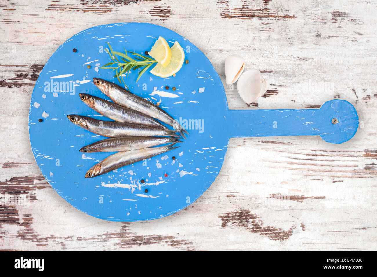 De délicieuses sardines fraîches sur cuisine en bois avec du citron, romarin et poivre colorés sur tableau blanc Banque D'Images