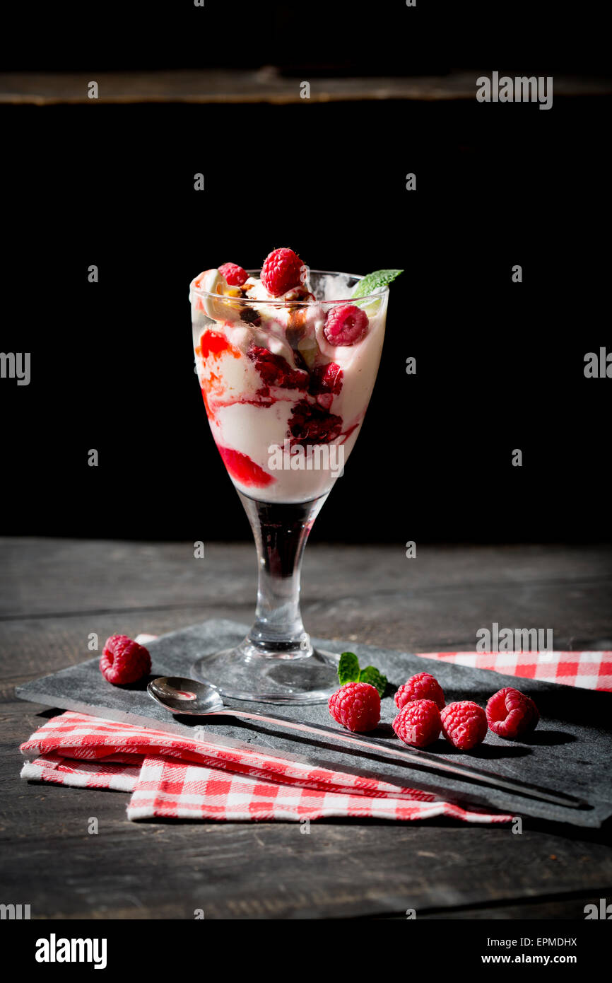Verre de glace vanille Bourbon avec sauce au chocolat et framboises chaudes Banque D'Images
