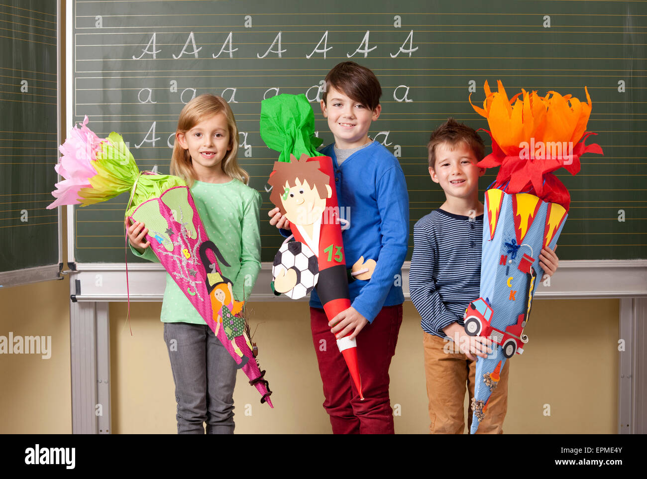 Les élèves heureux avec cônes de l'école at blackboard Banque D'Images