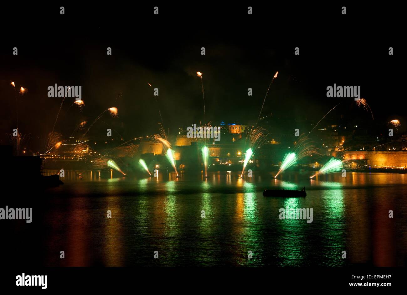 D'artifice. D'artifice coloré avec arrière-plan de La Valette, grosse explosion, maison lumière, reflets verts sur un plan d'eau à la Valette Banque D'Images