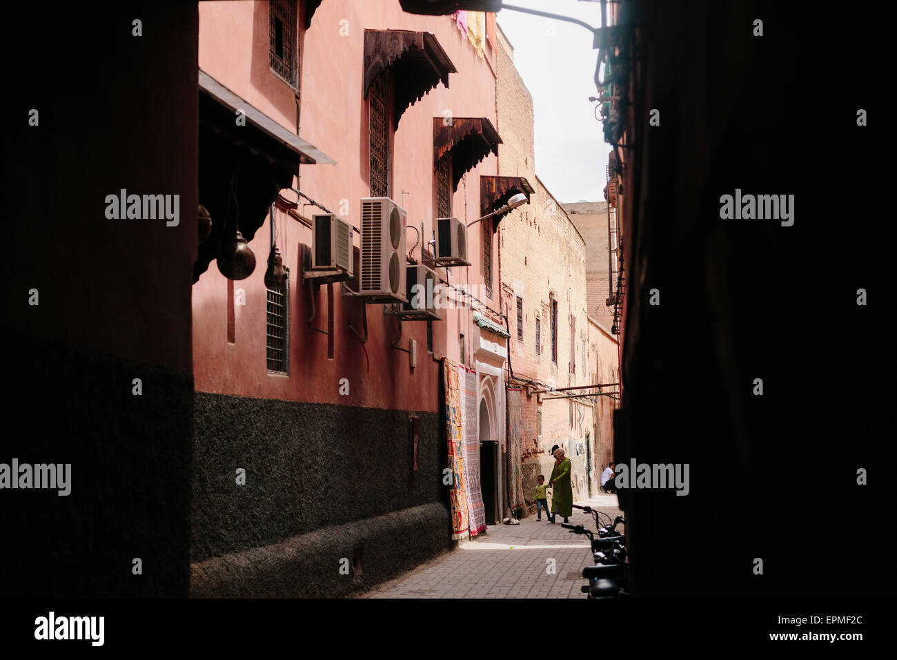 La vie de la rue dans le mellah (quartier juif) de Marrakech, Maroc. Une dame se promène avec son enfant le long d'une des rues étroites. Banque D'Images