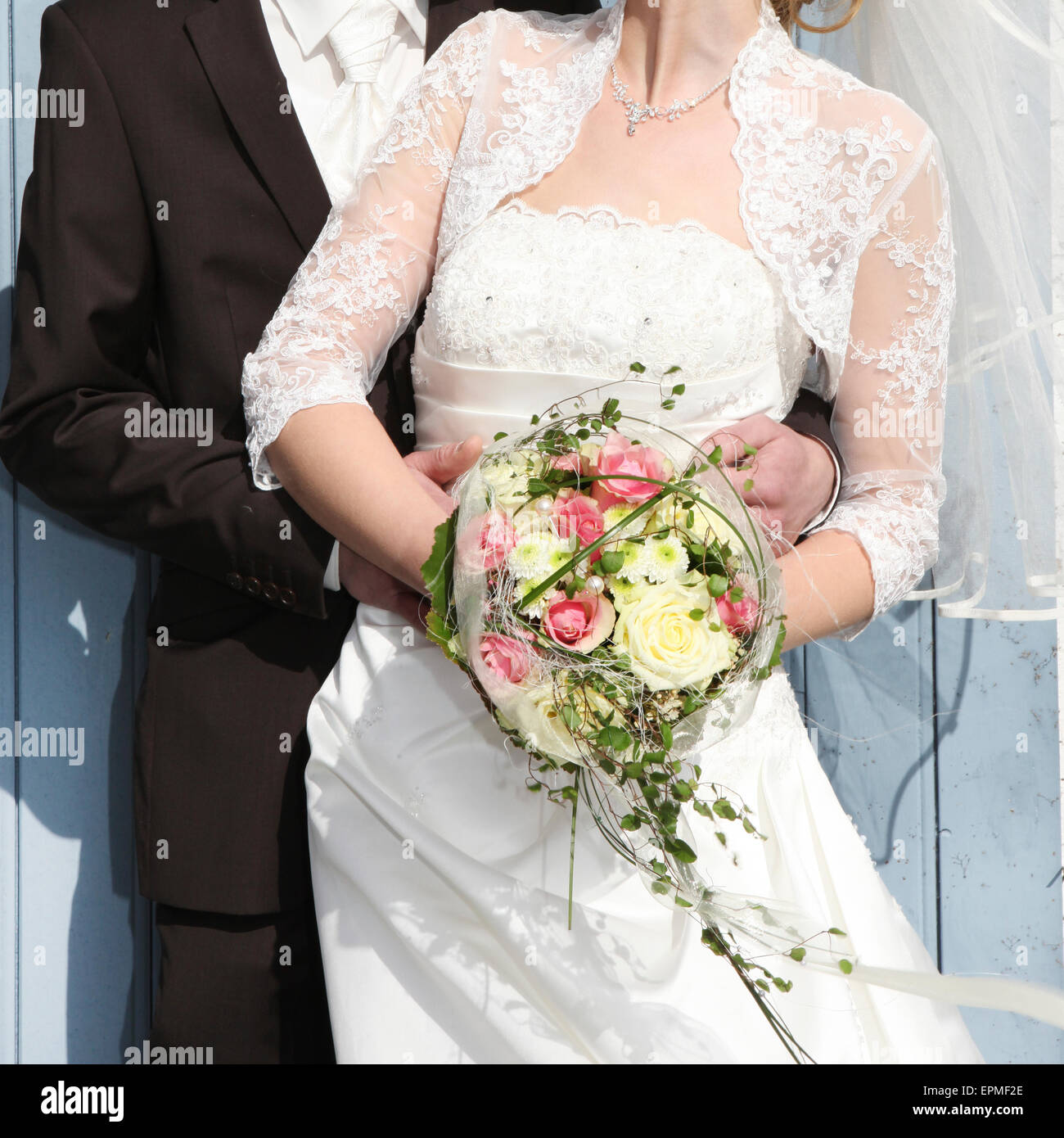 Une mariée dans une robe de mariée blanche avec un bouquet dans sa main est tenue par son fiancé Banque D'Images