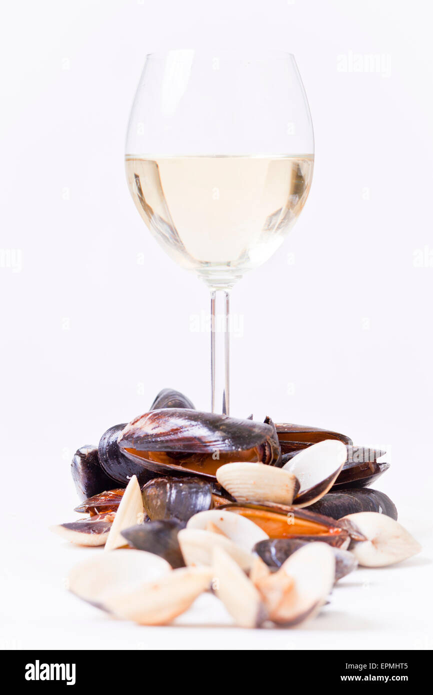 Les moules et les coques avec un verre de vin blanc sur un fond blanc. Banque D'Images