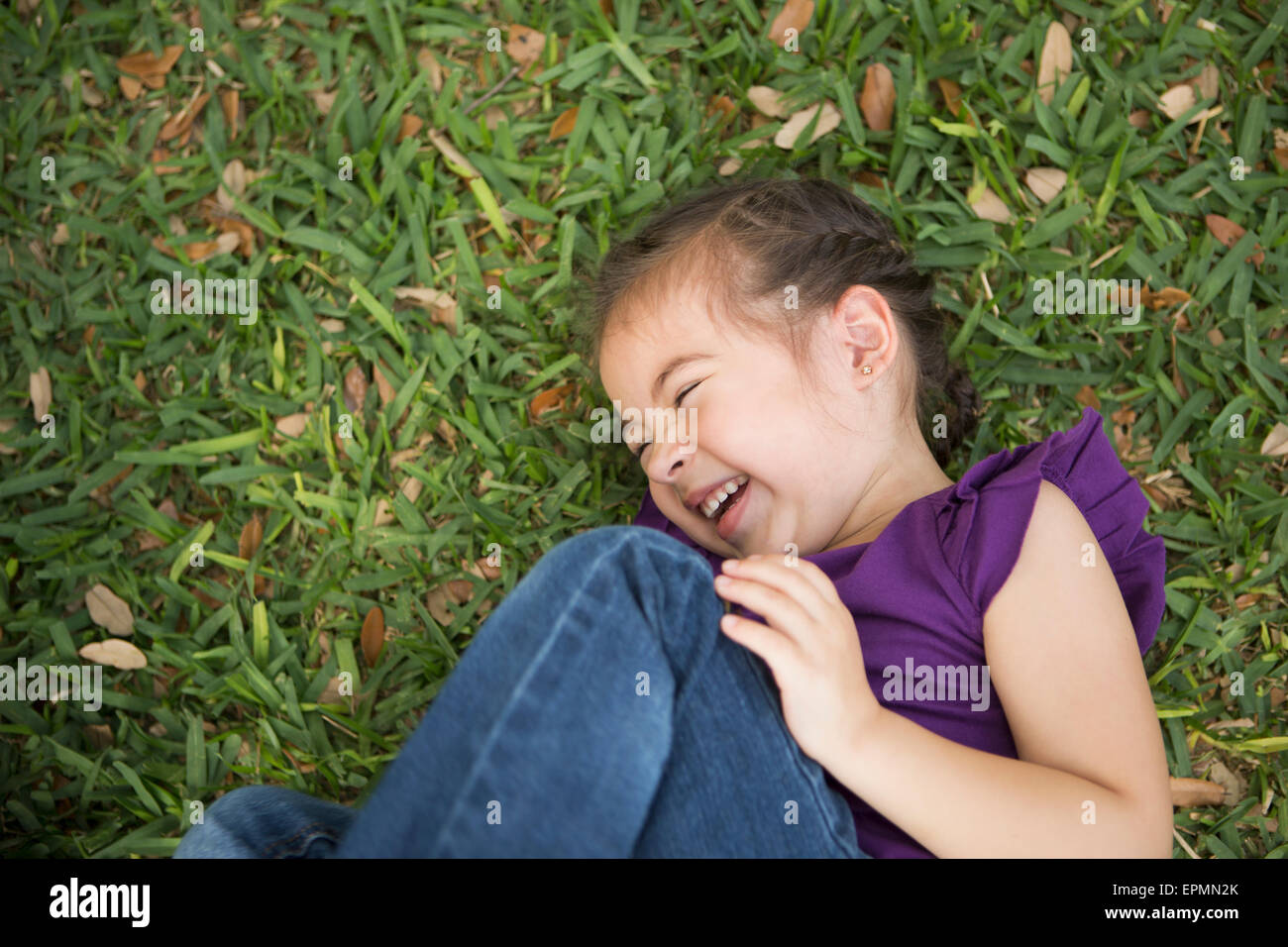 Une jeune fille couchée sur le côté avec les genoux rédigé en riant. Banque D'Images