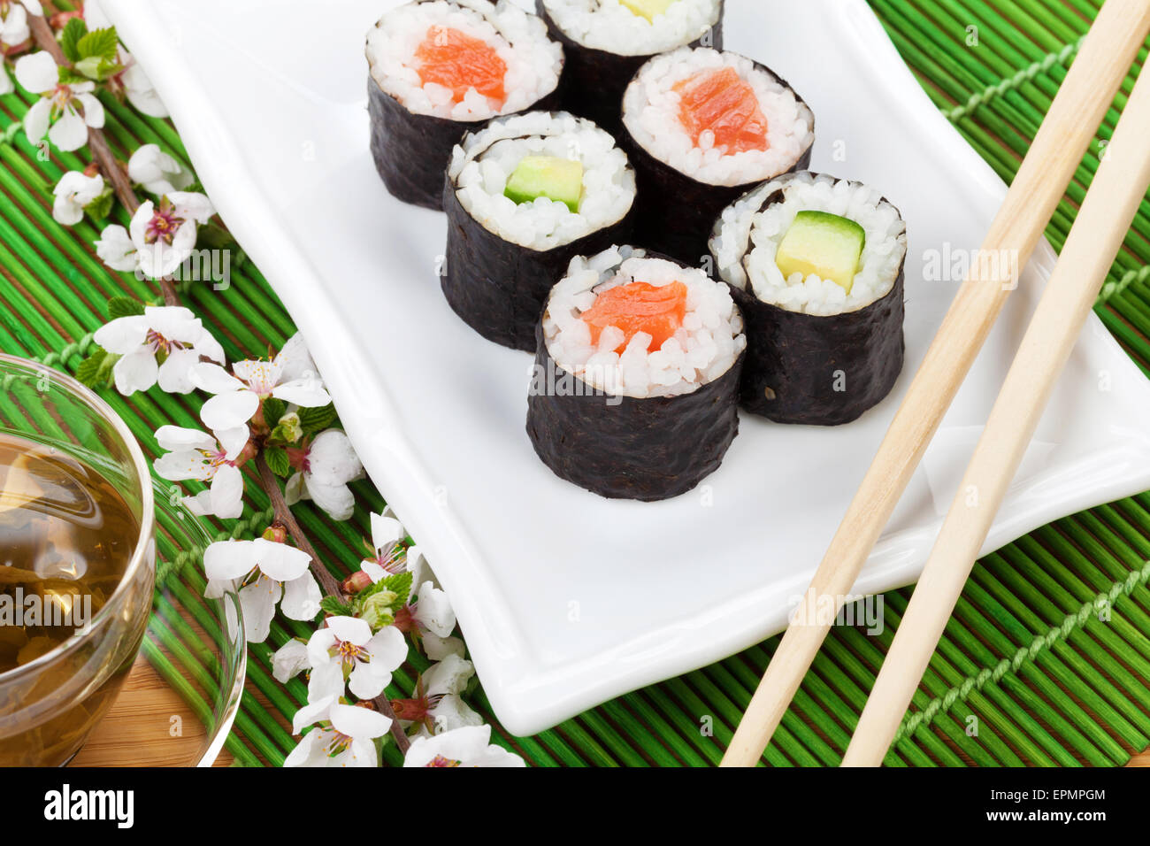 Sushi maki set, thé vert et sakura branche sur table en bambou Banque D'Images