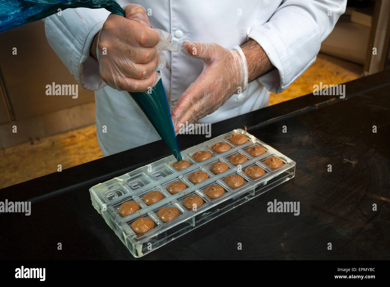 Un chocolatier prépare des bonbons de chocolat noir avec une poche à pâtisserie Banque D'Images
