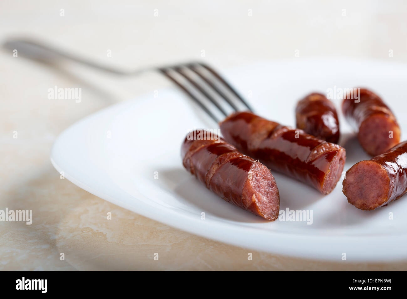 Tranches de saucisses et d'une fourchette sur une assiette blanche Banque D'Images
