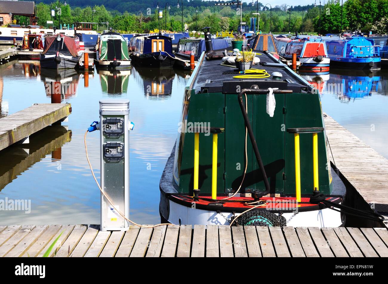 Narrowboats sur leurs amarres raccordés à l'électricité dans le bassin du canal, Barton Marina, Barton-under-Needwood, UK. Banque D'Images