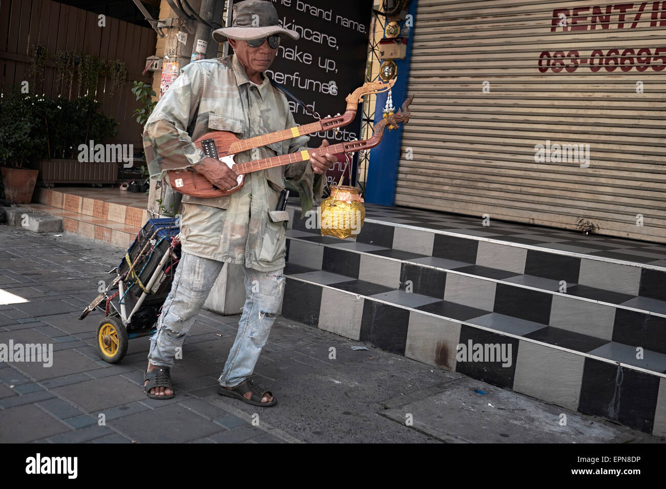 Bustier. Un buker de rue aveugle en Thaïlande jouant à la guitare traditionnelle à double cou Phin lute. Banque D'Images