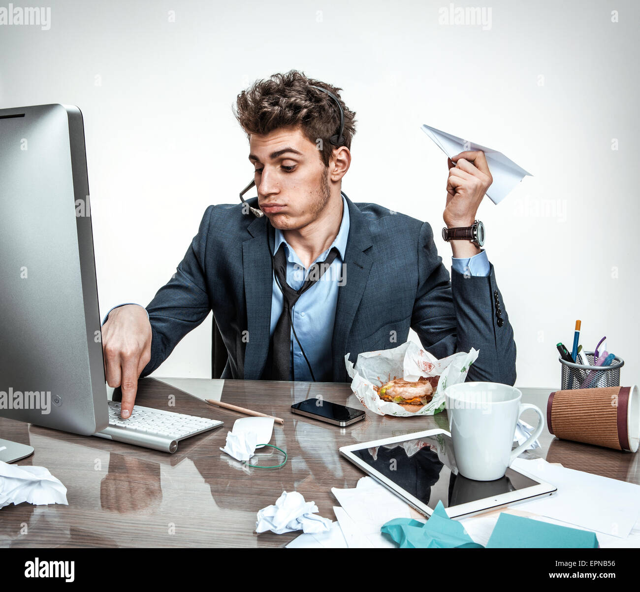 Jeune homme de bureau avec avion en papier dans la main de la saisie sur un clavier d'ordinateur de bureau moderne / place de travail à l'homme, l'indolence et lazi Banque D'Images
