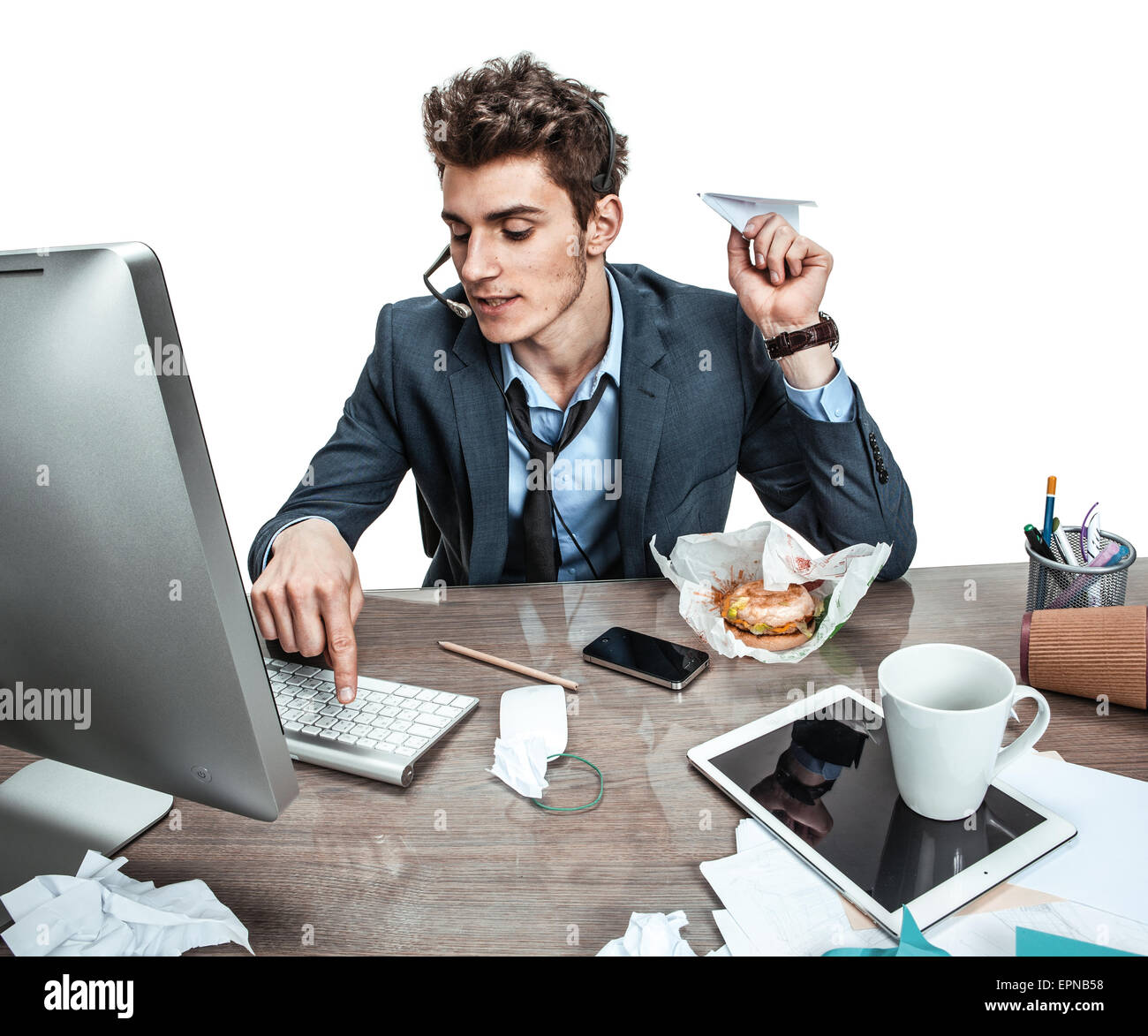 Guy with paper plane dans sa main la saisie sur un clavier d'ordinateur de bureau moderne / place de travail à l'homme, l'indolence et la paresse concept Banque D'Images