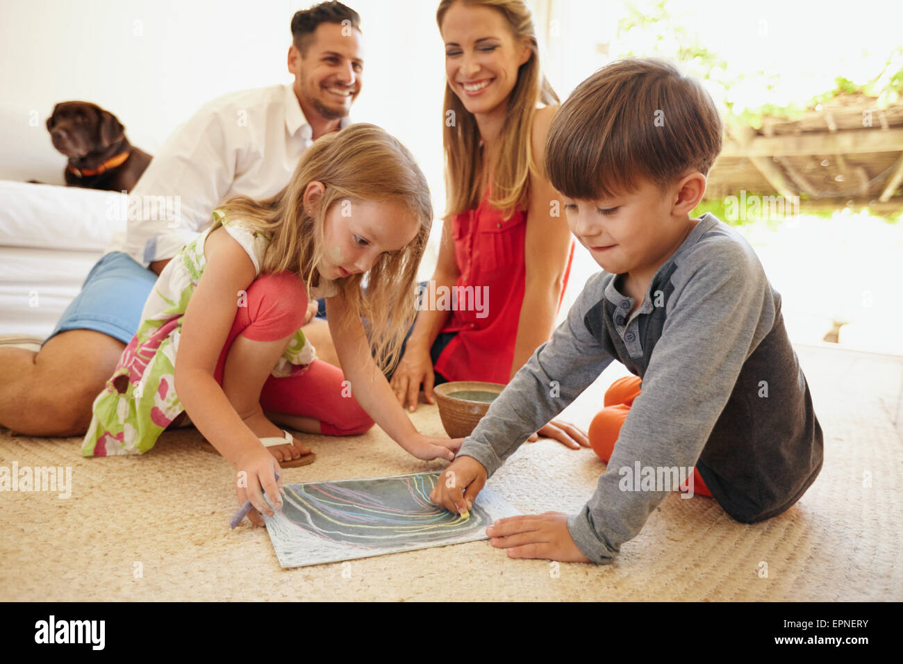 Petit garçon et fille le dessin avec les couleurs de craie, assis sur parole. Dessin d'enfants avec leurs parents dans la salle de séjour. Banque D'Images