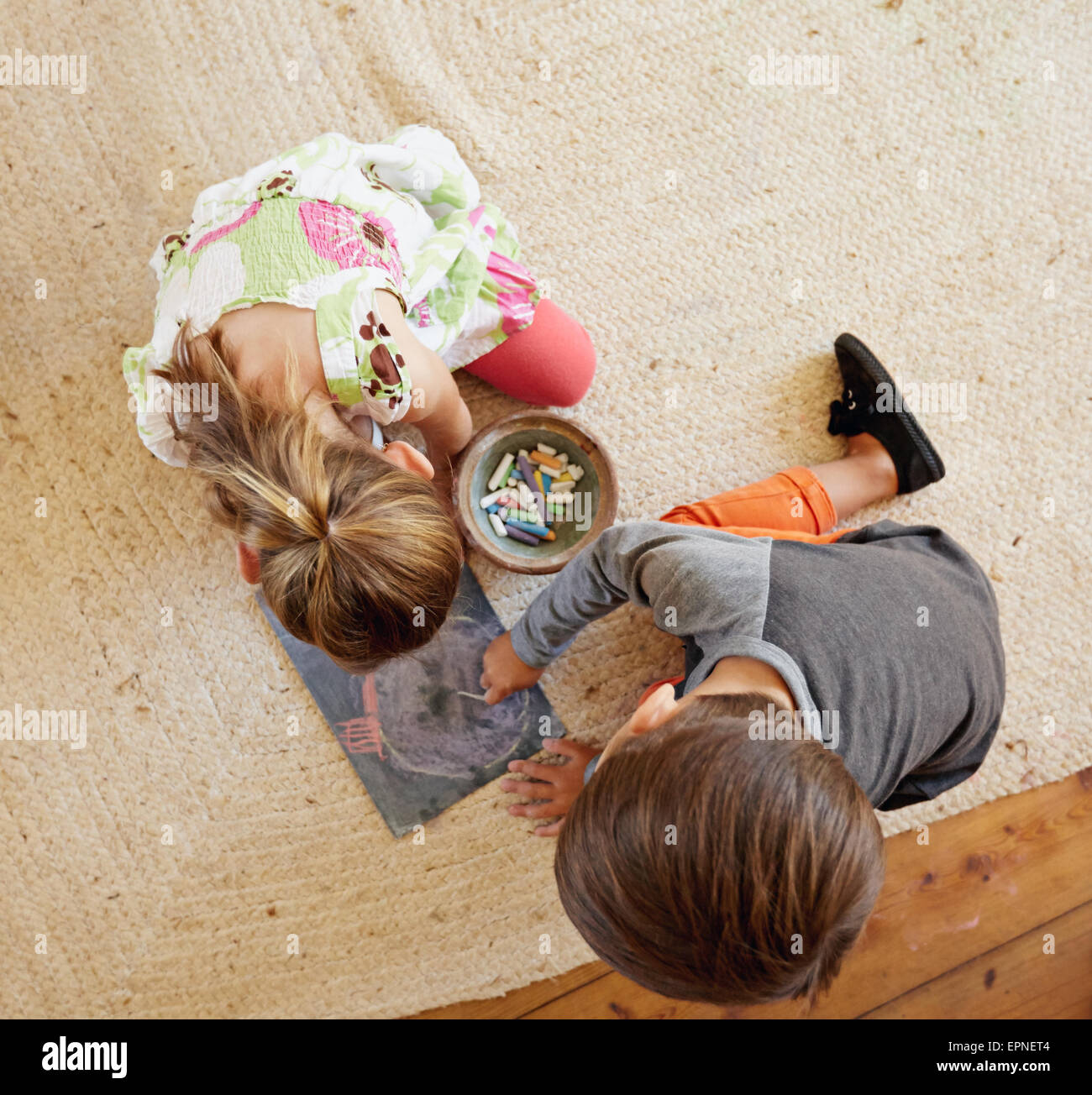 Vue de dessus deux petits enfants assis sur marbre dessiner avec les craies de couleur. Banque D'Images