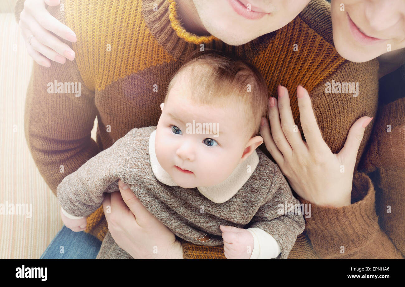 Une famille heureuse de trois, peu mignon bébé avec de grands yeux assis sur les genoux de la mère, la famille concept Banque D'Images