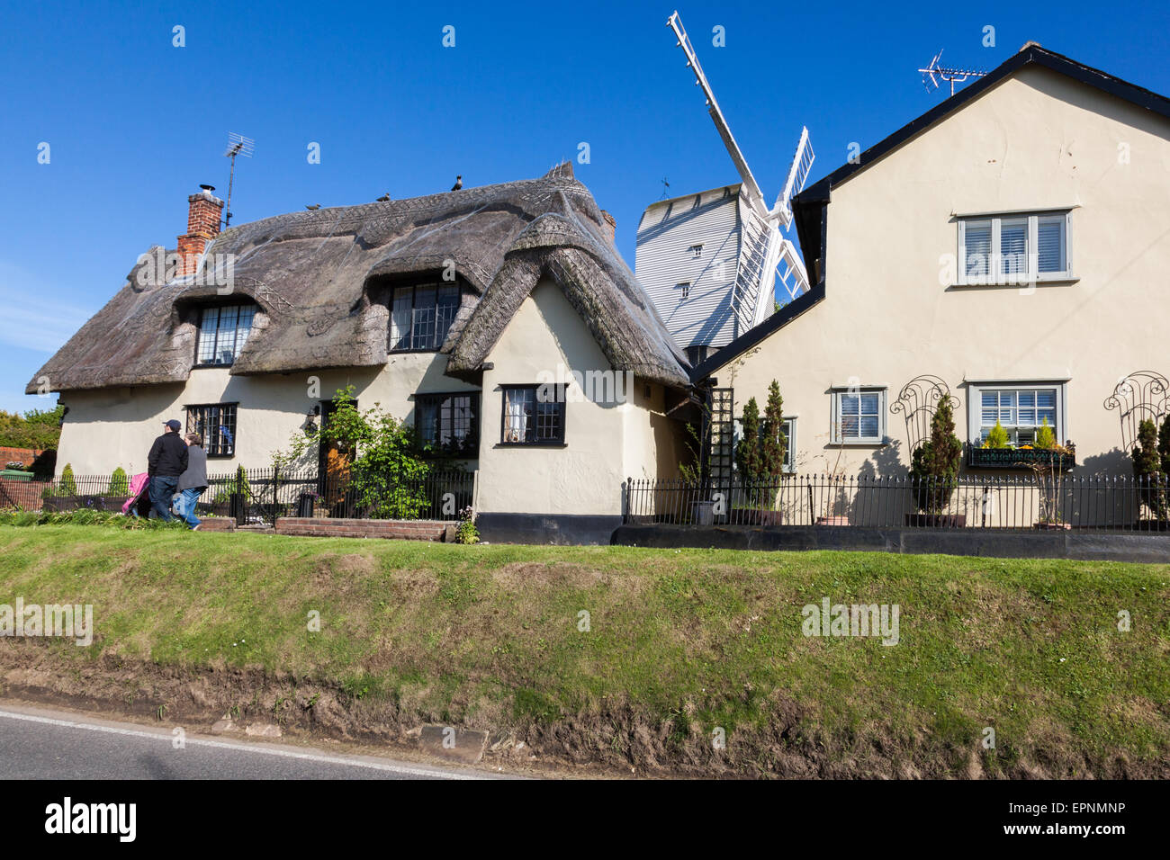 Un couple avec une poussette de marche passé Finchingfield chaumières avec le moulin derrière, Essex, Angleterre, Royaume-Uni Banque D'Images