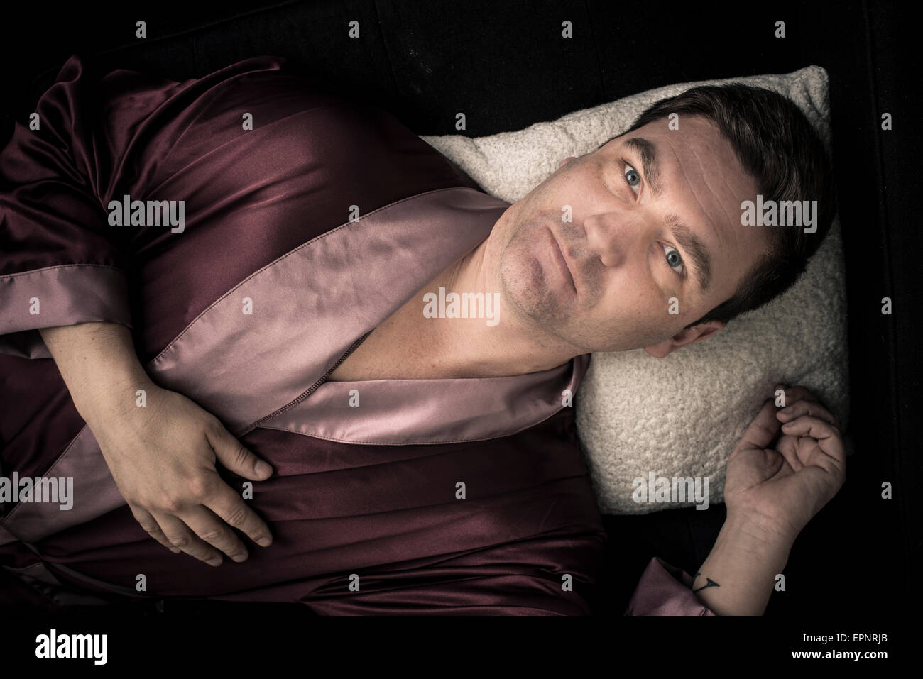 Homme étendu et se reposer sur un canapé à la maison. Il est éveillé, fixant le plafond avec un regard pensif et déprimés. Banque D'Images