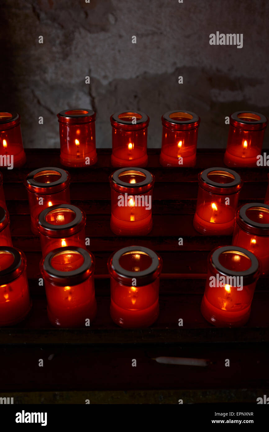 La prière chrétienne allumé des bougies votives dans une église catholique. Banque D'Images