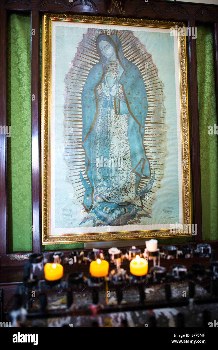 Peinture de notre-Dame de Guadalupe Cathédrale de Grenade Nicaragua // GRENADE, Nicaragua — Une peinture de notre-Dame de Guadalupe orne l'intérieur de la Cathédrale de Grenade, entourée d'offrandes votives de fidèles dévots. La cathédrale, officiellement connue sous le nom de cathédrale de Grenade ou Catedral de Granada, est l'un des monuments religieux les plus importants du Nicaragua, datant de la période coloniale. L'image de notre-Dame de Guadalupe représente la Vierge Marie telle qu'elle serait apparue à Juan Diego au Mexique en 1531, et est devenue une icône religieuse importante dans toute l'Amérique latine. Votive de Banque D'Images