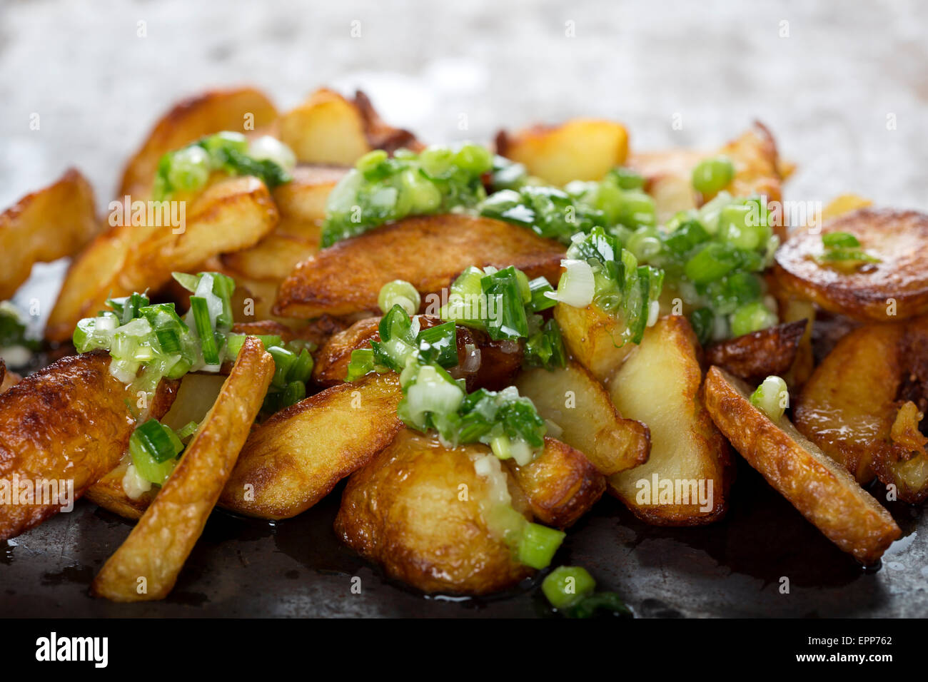 Des quartiers de pommes de terre frites croustillantes avec de l'ail vert Banque D'Images
