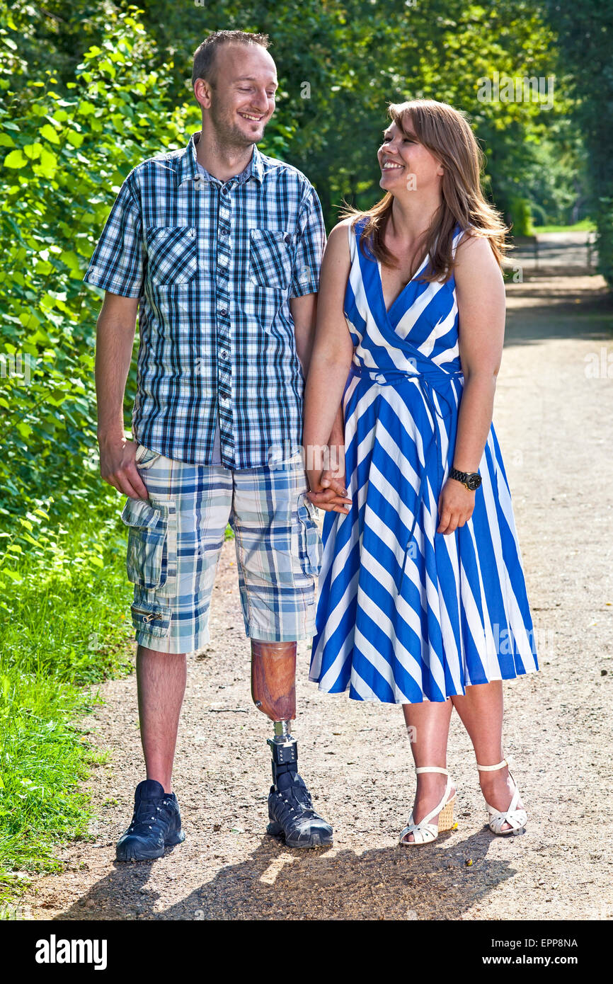 Beau mobilité homme portant une jambe artificielle debout avec sa jeune amie de sa belle sur un chemin rural, en souriant. Banque D'Images