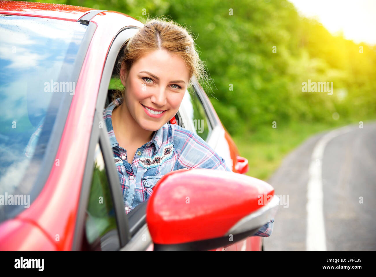 Happy smiling girl dans une voiture rouge. Au coucher du soleil. Concept de voyage. Banque D'Images