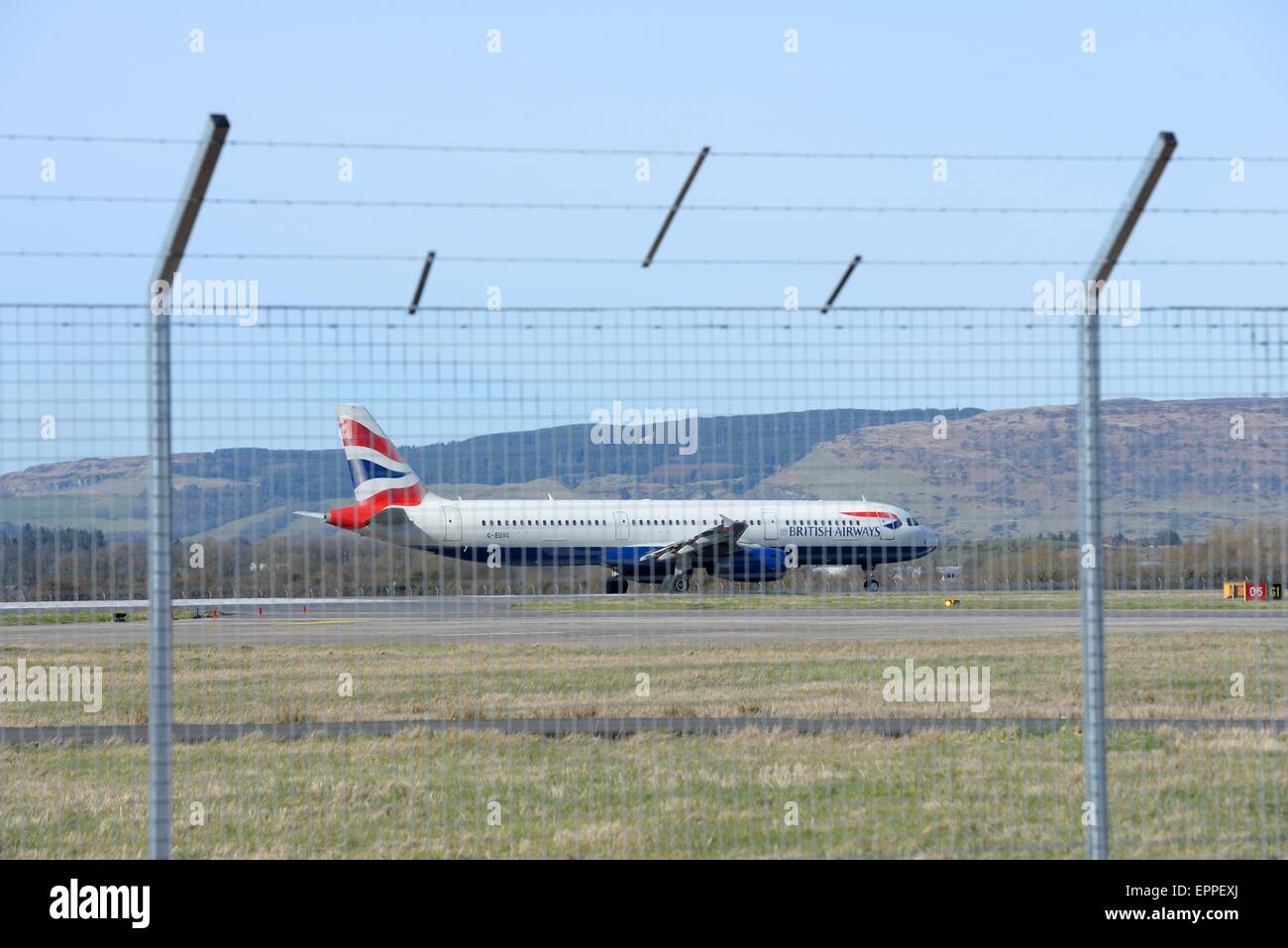 Un avion de British Airways se prépare au décollage Vue de derrière le mur de sécurité à l'aéroport international de Glasgow, Ecosse Banque D'Images