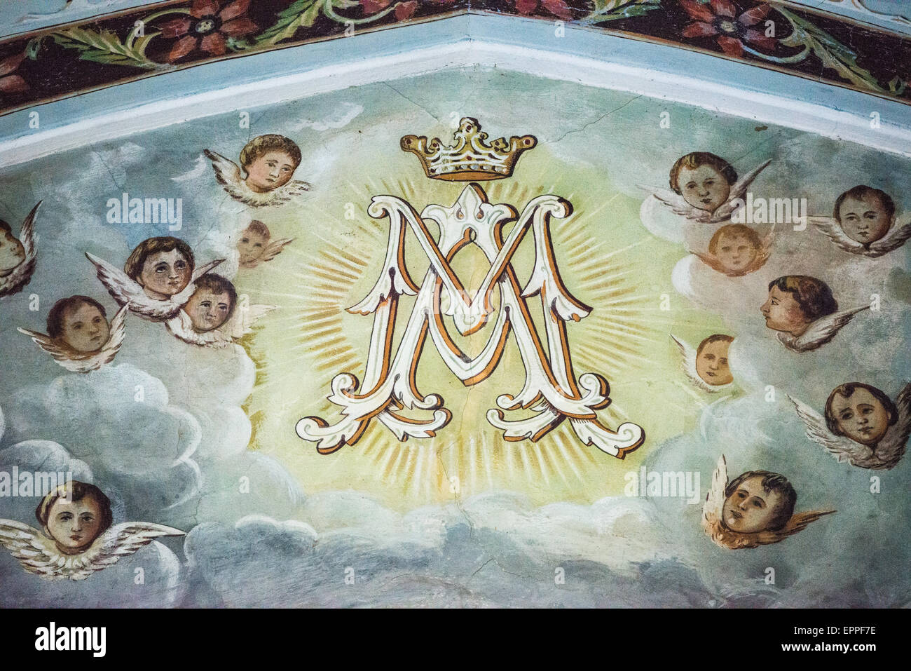 Marie aide des Chrétiens Monogramme peinture Grenade Nicaragua // GRENADE, Nicaragua — Une peinture religieuse avec un monogramme des lettres 'M A' avec une couronne au-dessus, entouré d'anges, orne les murs supérieurs de la Capilla Maria Auxiliadora (chapelle Marie aide des Chrétiens). Les œuvres d'art font partie de l'intérieur somptueusement décoré de la chapelle, qui présente des murs bleu pastel et vert distinctifs. Située dans la partie ouest de Grenade, cette chapelle catholique est dédiée à Marie aide des chrétiens, titre de dévotion donné à la Vierge Marie. Le monogramme représente 'Maria Auxiliadora', combin Banque D'Images