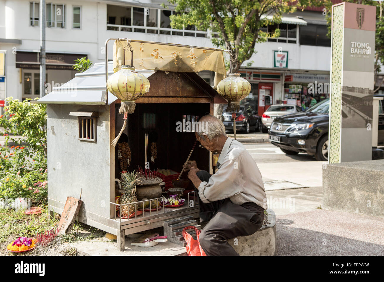 Un homme s'allume de l'encens dans un petit côté route de culte dans la région de Tiong Bahru Singapour. Banque D'Images