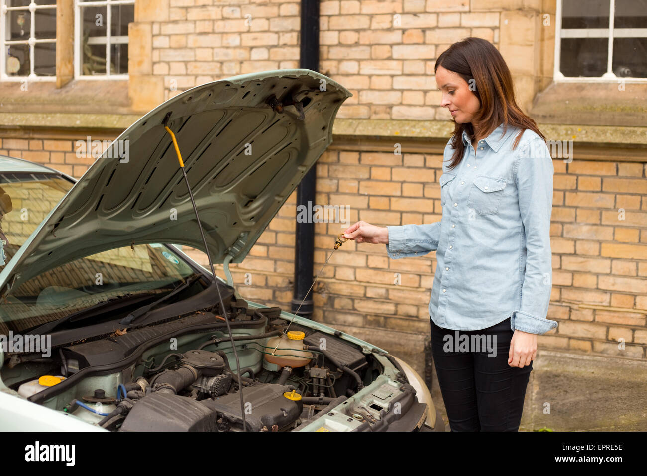 Jeune femme de vérifier le gage sur sa voiture Banque D'Images