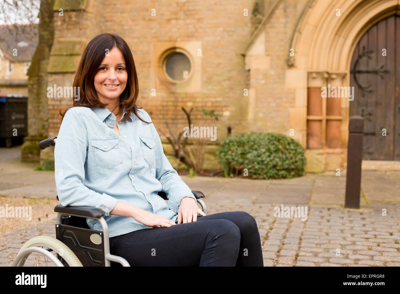 Jeune femme dans un fauteuil roulant à l'extérieur d'une église Banque D'Images