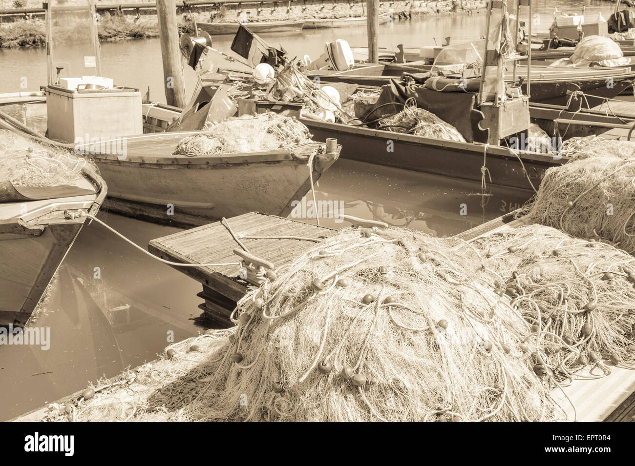 Effet vintage des filets de pêche sur le quai, dans l'arrière-plan les bateaux de pêche Banque D'Images
