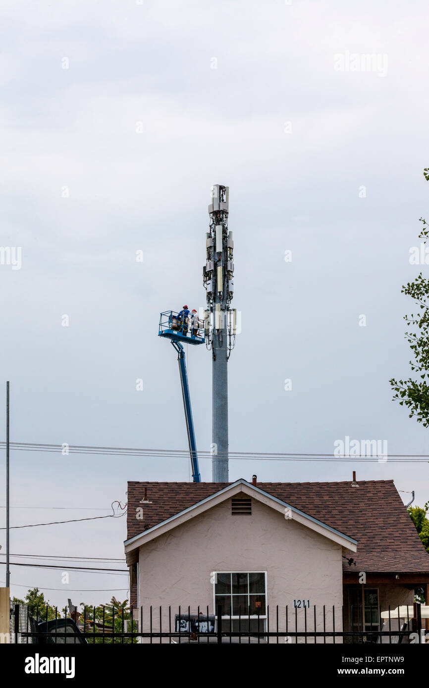 Deux hommes travaillant à partir d'un ascenseur godet sur une tour de téléphonie cellulaire ou mobile dans la région de Modesto en Californie Banque D'Images