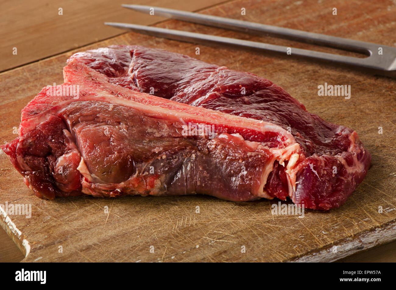 Le boeuf cru t-bone steak sur la table en bois sombre. Banque D'Images