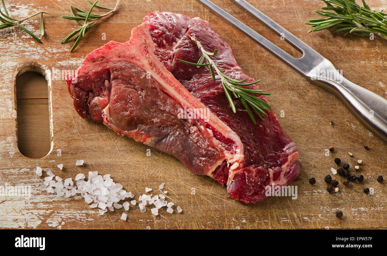 Le boeuf cru t-bone steak sur une table en bois. Banque D'Images